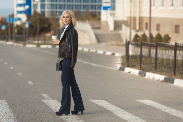 Beautiful blonde woman cross the road with a take away coffee
