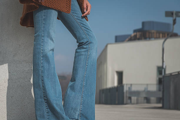 Detail of a girl wearing flared jeans and posing in an urban context