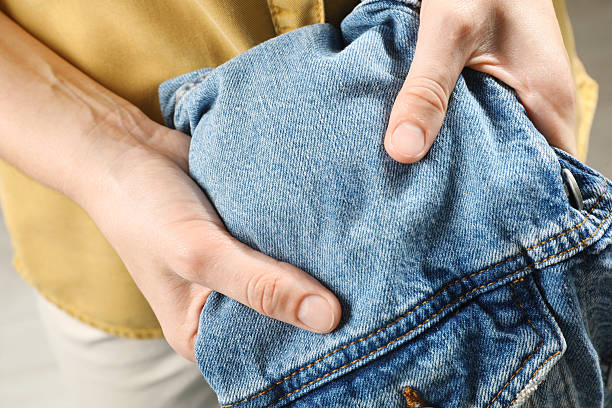 Washing clothes. Woman holding jeans with stain, closeup