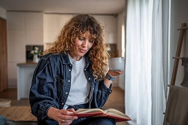 Young woman sitting on a bed, savoring a peaceful moment with a book