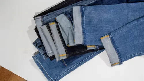 A Pile Of Denim Jeans Sitting On Top Of A Wooden Floor